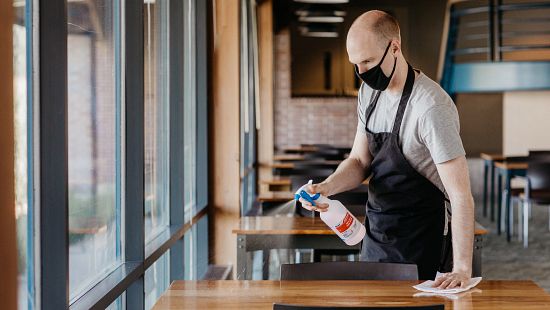Restaurant staff cleaning table with disinfectant that kills covid 19.
